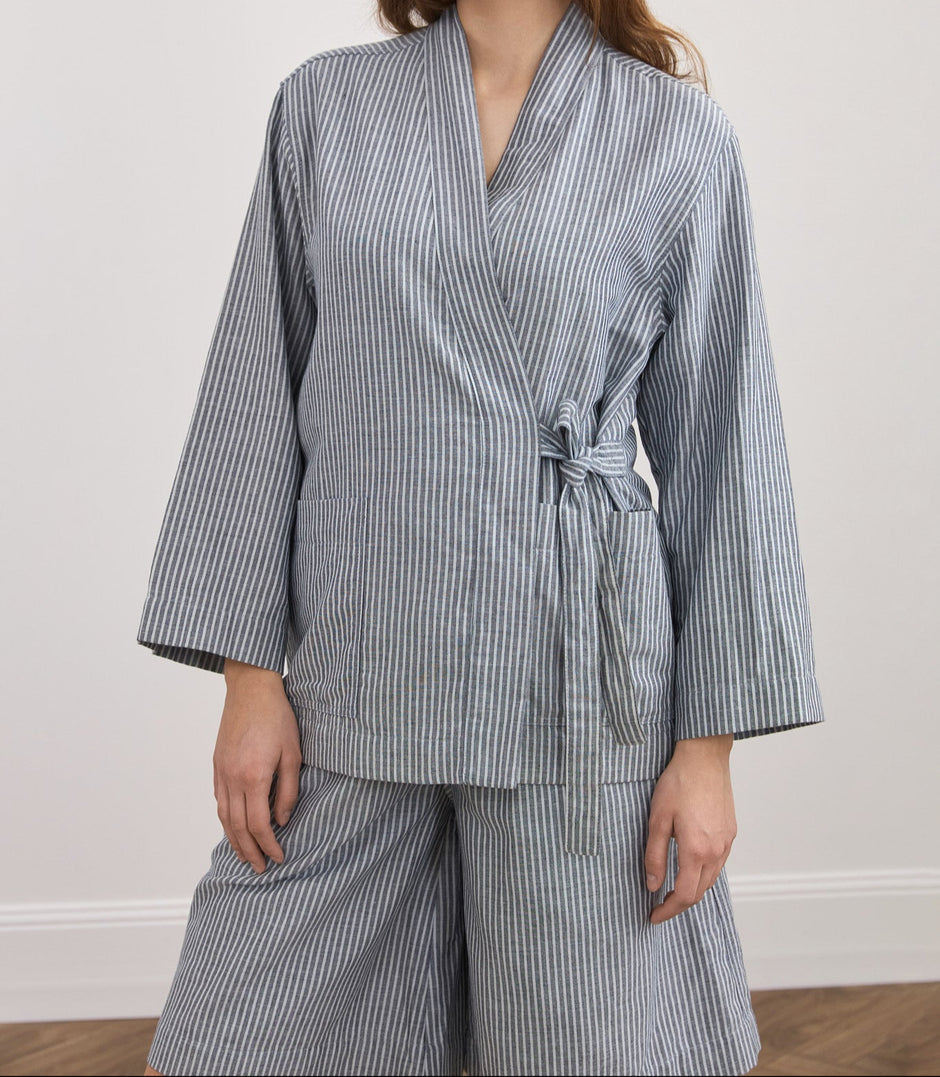 Woman wearing a blue and white striped kimono against a plain background