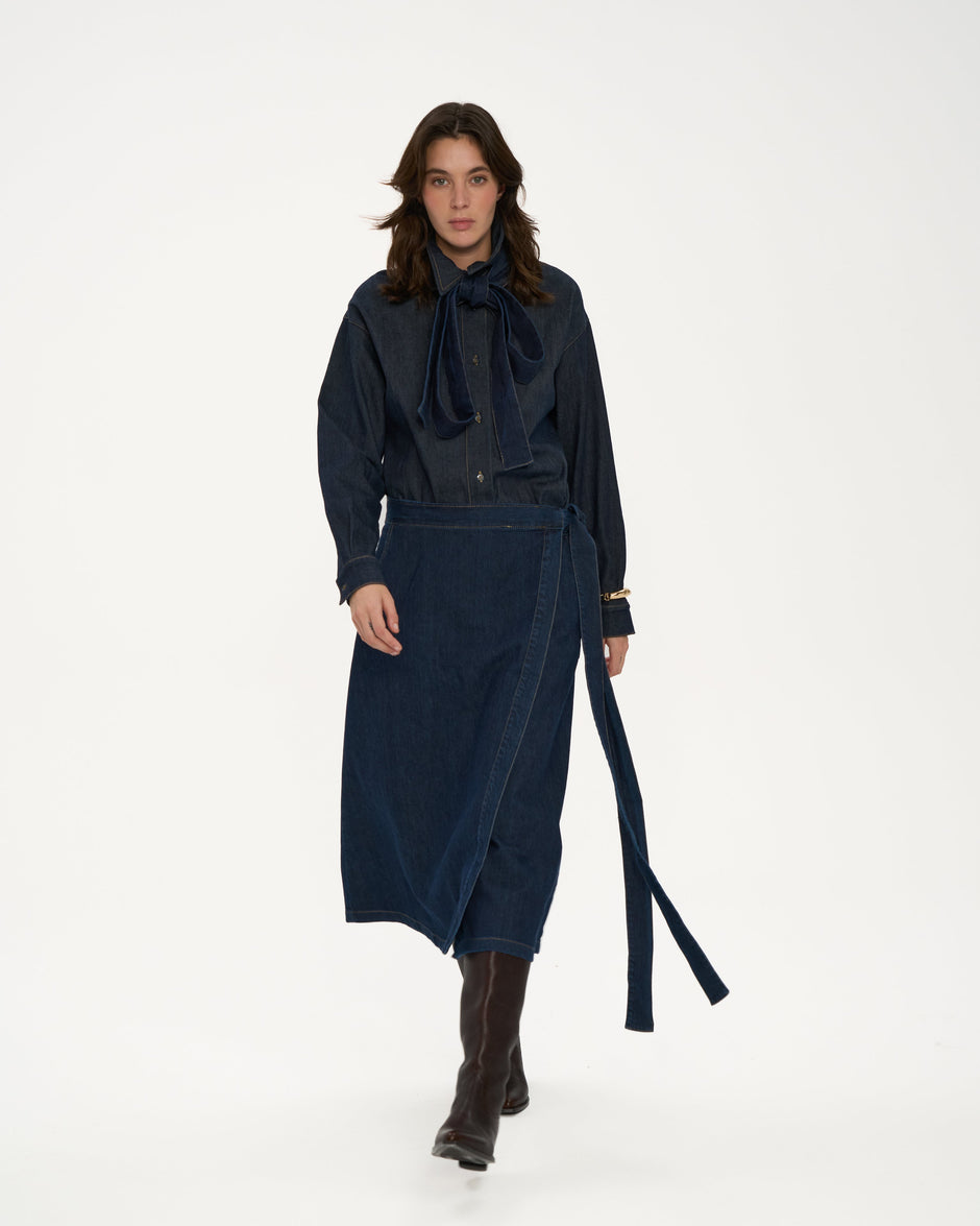 Woman wearing a dark blue outfit with a long scarf on a white background