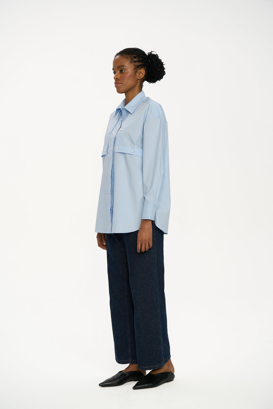 Woman wearing a light blue shirt and dark pants on a white background