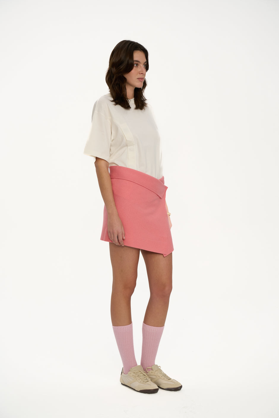 Woman wearing a white top and pink skirt on a white background