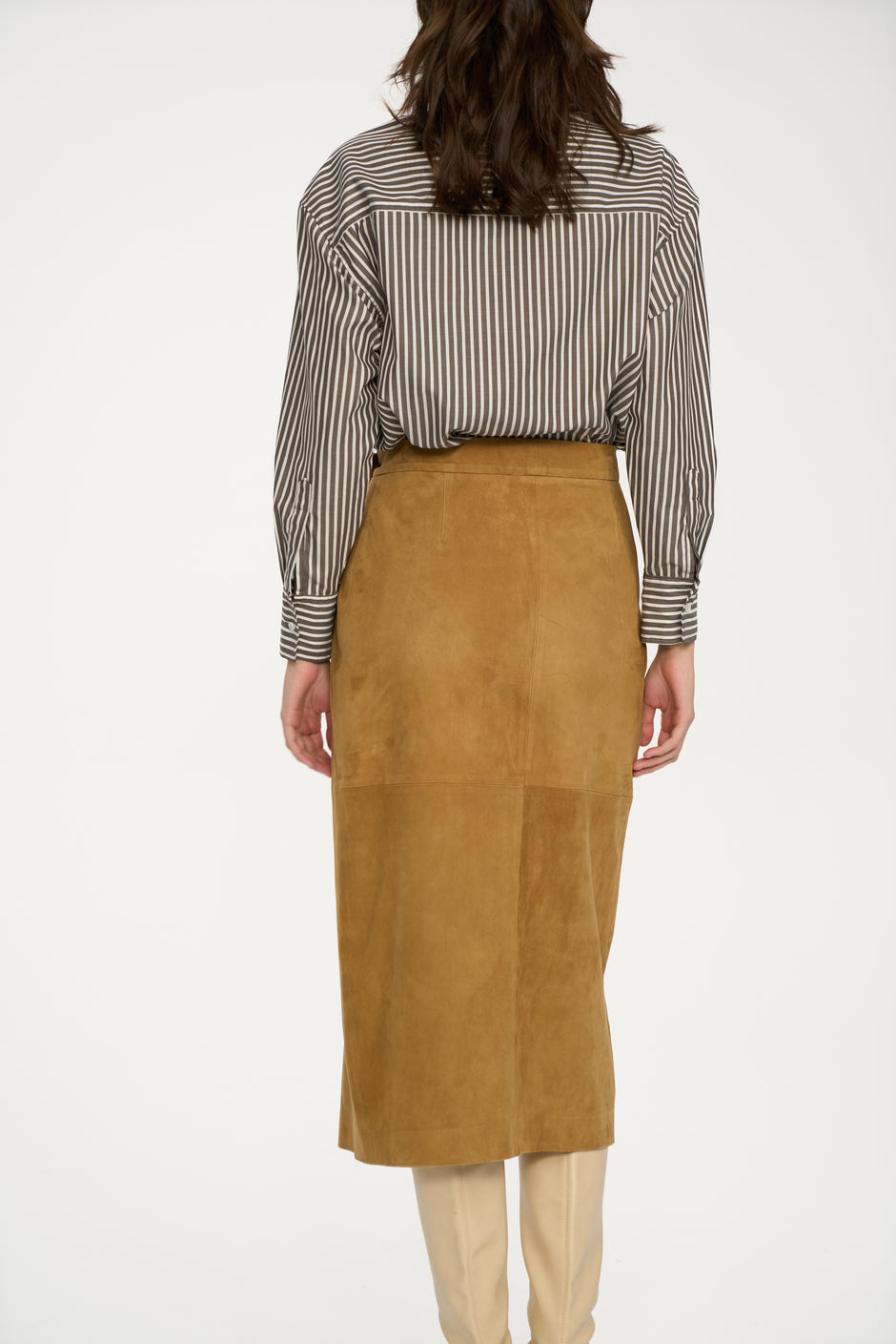 Person wearing a striped shirt and tan suede skirt on a white background