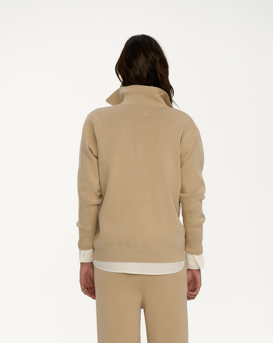 Person wearing a beige sweater and pants set on a white background