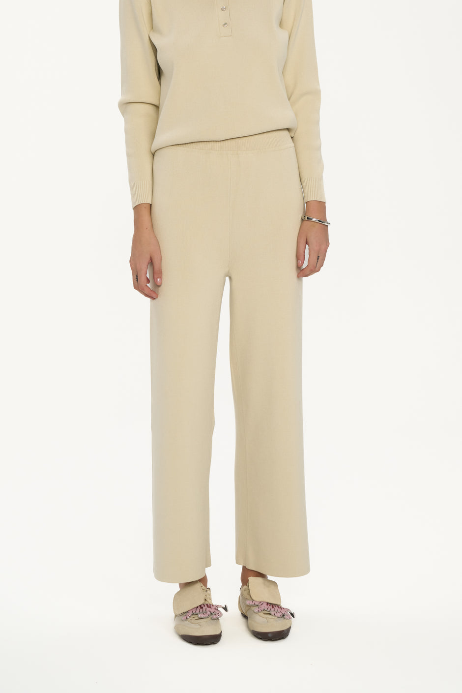 Person wearing a beige outfit with pants on a white background