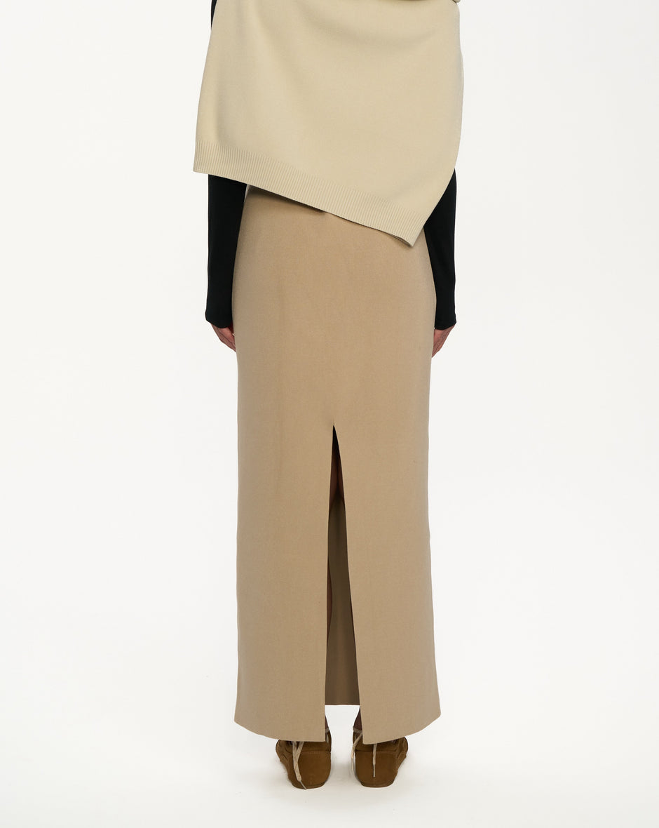 Person wearing a beige scarf and beige pants on a white background