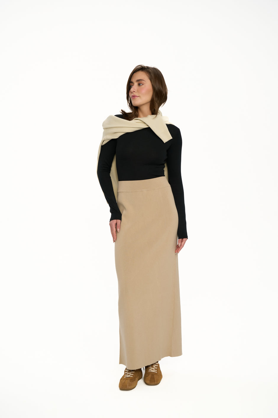 Woman wearing a black top and beige skirt with a matching shawl on a white background