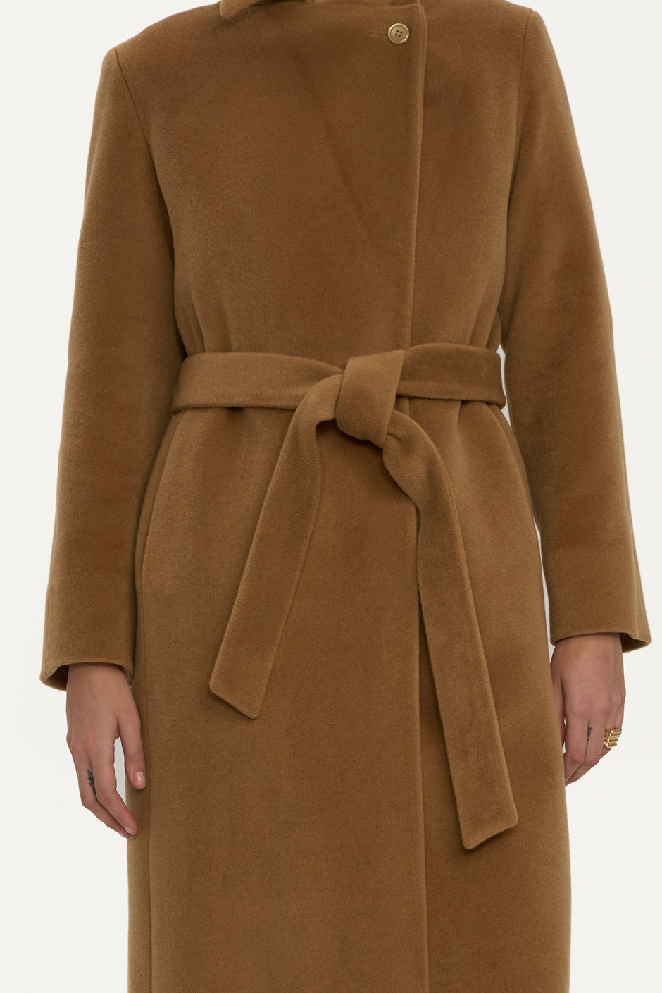 Detail of camel wool wrap coat with wide lapels and belt styled over beige knit polo and knit trousers – Inner Tiger