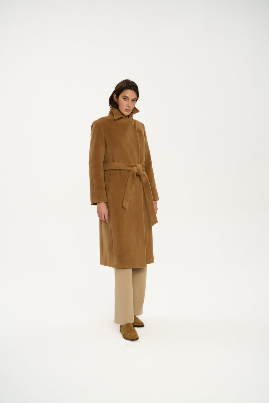 Camel wool wrap coat with belt styled over beige trousers and loafers, three-quarter full length view on model – Inner Tiger